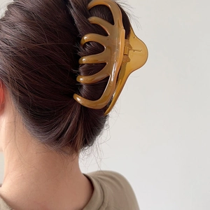 Close-up of a large translucent amber hair claw clip worn on hair for a secure styling