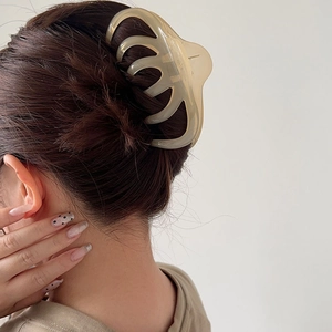 Rear view of a model wearing a large translucent daisy hair claw clip for a bun hairstyle
