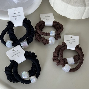 Close-up of elegant black and brown hair ties with pearl beads and square accents