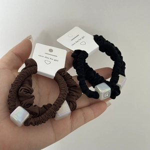 Detail showing black and dark brown hair ties with colorful cubic acrylic bead decorations