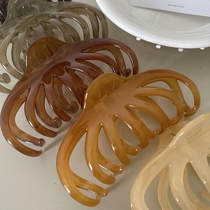 Detail of glossy resin octopus hair claws in deep green, amber, and cream colors