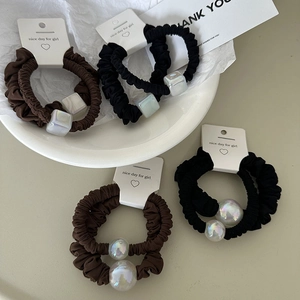 French style brown and black hair ties with iridescent square beads and pearls in a ceramic dish