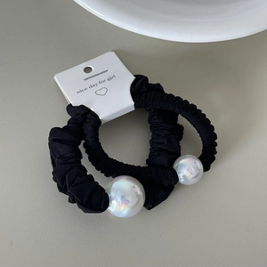 Detail of two black scrunchies with large iridescent faux pearls on display card