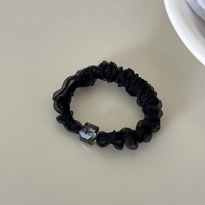 Detail of a black organza scrunchie with a translucent grey square bead accessory