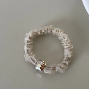 Detail showing sheer champagne organza scrunchie with a square crystal bead accent