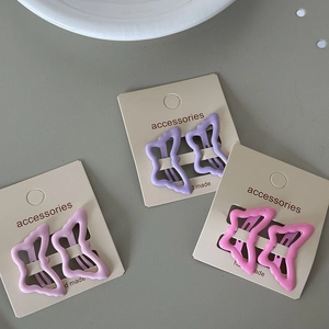 Detailed view of matte butterfly hair clips in purple and pink on display cards