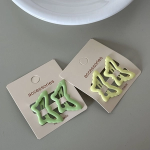 Detail of butterfly hair clips in green and yellow lacquer on white card display