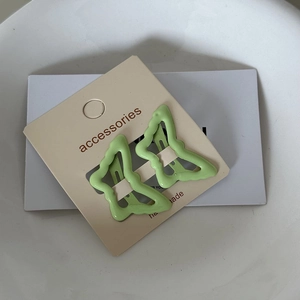 Detail showing two wavy star-shaped green hair clips on a cream accessory card