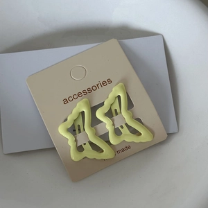 Detailed macro view of yellow butterfly hair clips on a white brand display card