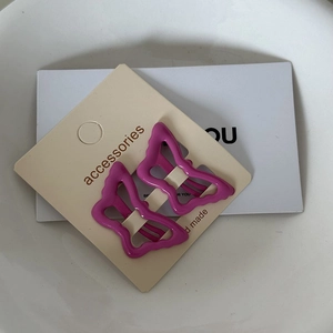 Detail of pink butterfly hair clips on a white display card with a sleek alloy finish