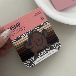 Detailansicht elastischer Haargummis in braunen Farbtönen auf einer rosa Cartoon-Karte