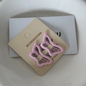 Close-up of two pink butterfly metal hair clips on a handmade accessories display card