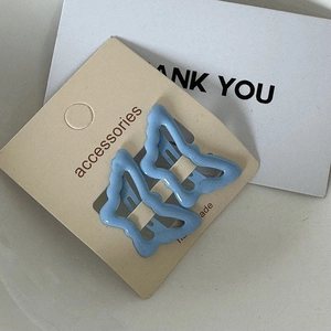 Detail of blue wavy butterfly hair clips on beige accessory card with modern design