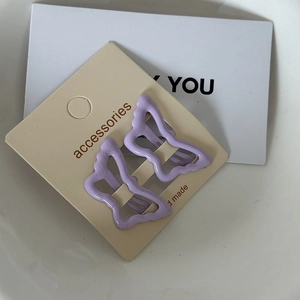 Close-up of two purple butterfly metal hair clips with matte finish on card
