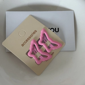 Close-up of two pink butterfly hair clips with wave-edged metal cutout and glossy finish
