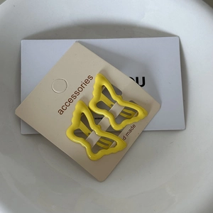 Detailed macro view of two bright yellow butterfly hair clips on a beige product card