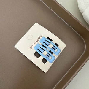 Détail de pinces à cheveux ondulées bleu clair sur carte de présentation blanche