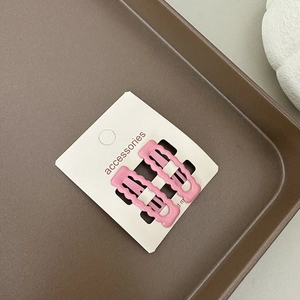 Détail de deux barrettes roses mates aux bords ondulés sur une carte de support
