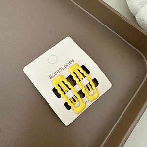 Détail de deux pinces à cheveux ondulées jaune vif sur une carte de présentation blanche