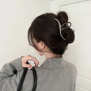 Detail view of large silver metal wave hair claw clip securing a stylish low bun