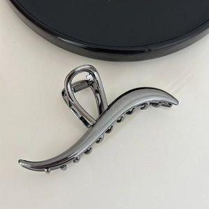 Detail view of large dark grey metal wave hair claw clip with polished finish and grip teeth