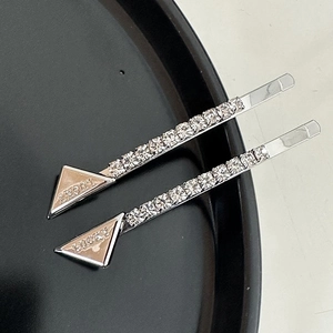 Close-up of silver triangle hair clips with rhinestones and LUCKY engraved lettering