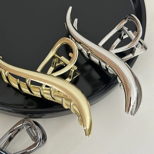 Detailed view of large wave metal hair claws in gold, silver, and gunmetal finishes