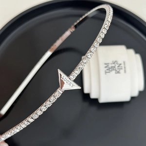 Detail of silver rhinestone headband featuring a triangular plate with Lucky engraving
