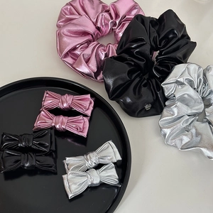 Gros plan de chouchous et barrettes nœuds en cuir rose, argenté et noir élégants