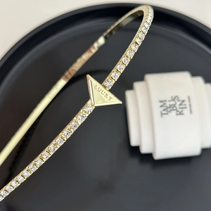 Macro view of gold metal headband with lucky triangle charm and pavé crystals