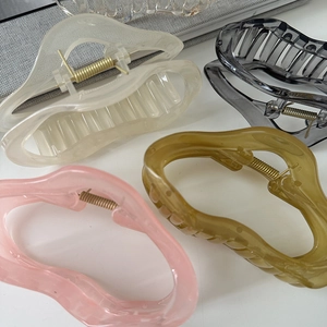 Close-up of four irregular resin hair claws in cream, pink, olive green, and transparent grey