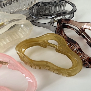 Macro shot of large wave resin hair claws in pink, yellow, and tortoiseshell colors