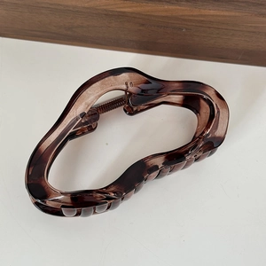 Detail of tortoiseshell resin hair claw clip with metallic spring and wavy grip design