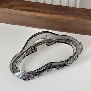 Detail shot of smoky gray translucent resin hair claw with wavy design and metal spring