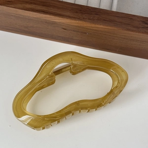Detailed view of amber resin hair claw clip with irregular wavy design and metal spring