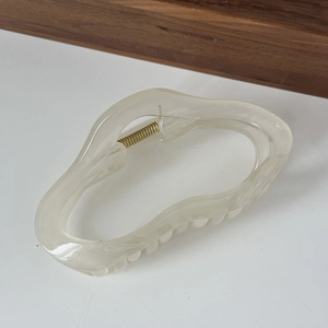 Macro shot of large irregular cream white resin hair claw clip with marble texture