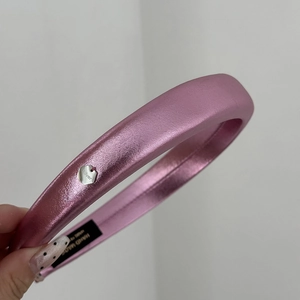 Détail macro du serre-tête rembourré en satin rose fait main avec pendentif cœur argenté