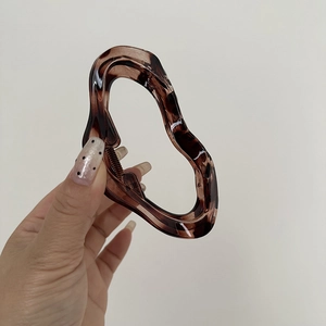 Detail view of a large tortoise shell resin shark hair claw with irregular wave design