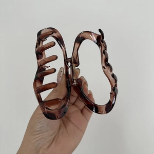 Detail showing the brown translucent large hair claw clip with wave curved edges