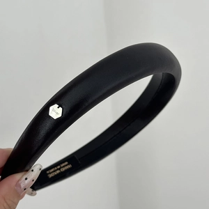 Détail du serre-tête en cuir noir fait main avec logo en métal argenté et doublure