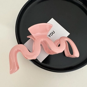Makro-Detail einer großen rosa gewellten Haarklammer auf einem stilvollen Präsentierteller