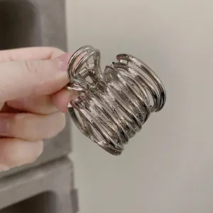 Detail of silver hollow multi-loop metallic hair claw clip with high-polish finish