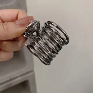 Detail of silver spiral metal hair claw clip with multi-layered circular design