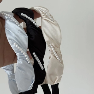Gros plan de serre-têtes en satin plissé avec perles décoratives en bleu, noir et beige