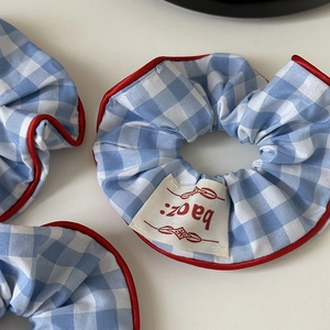 Detailansicht eines blau karierten Haargummis mit rotem Rand und feiner Textur