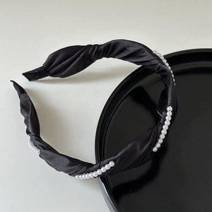Détail d'un serre-tête élégant en satin noir avec perles et texture à nœud croisé