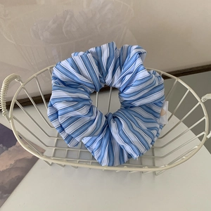 Detailed shot of a blue and white striped fabric scrunchie inside a white wire basket