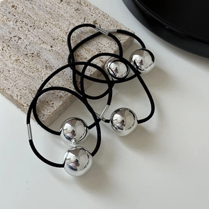 Detail of black elastic hair tie with a shiny silver metallic sphere on a stone tray
