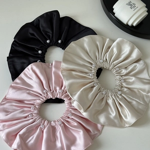 Detailed view of champagne, pink and black satin hair scrunchies with pearl trimmings