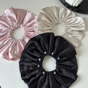 Detailed view of satin scrunchies with white pearls in pink, beige, and black colors